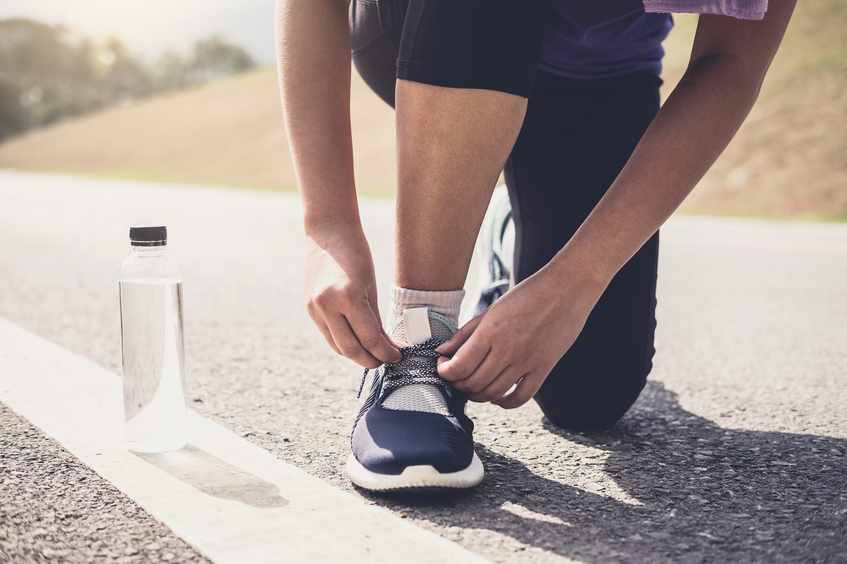 Mode de vie sain, coureur attachant ses chaussures de course pour se préparer à la course sur une piste d'athlétisme, jogging, concept de bien-être. Santé