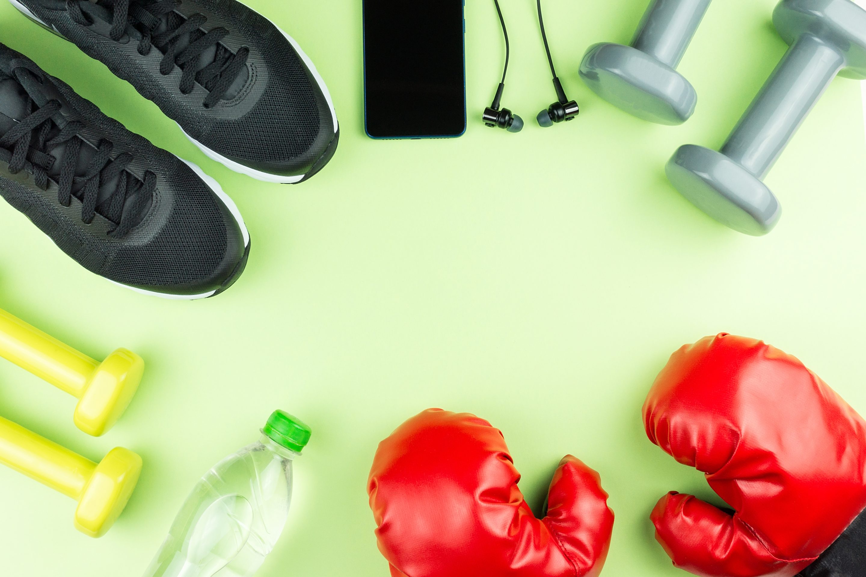 Équipement de fitness. Baskets, eau, haltères et écouteurs sur fond vert. Santé